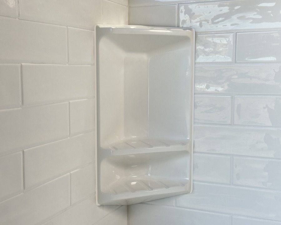 Two-tier cultured marble corner caddy mounted in a shower corner